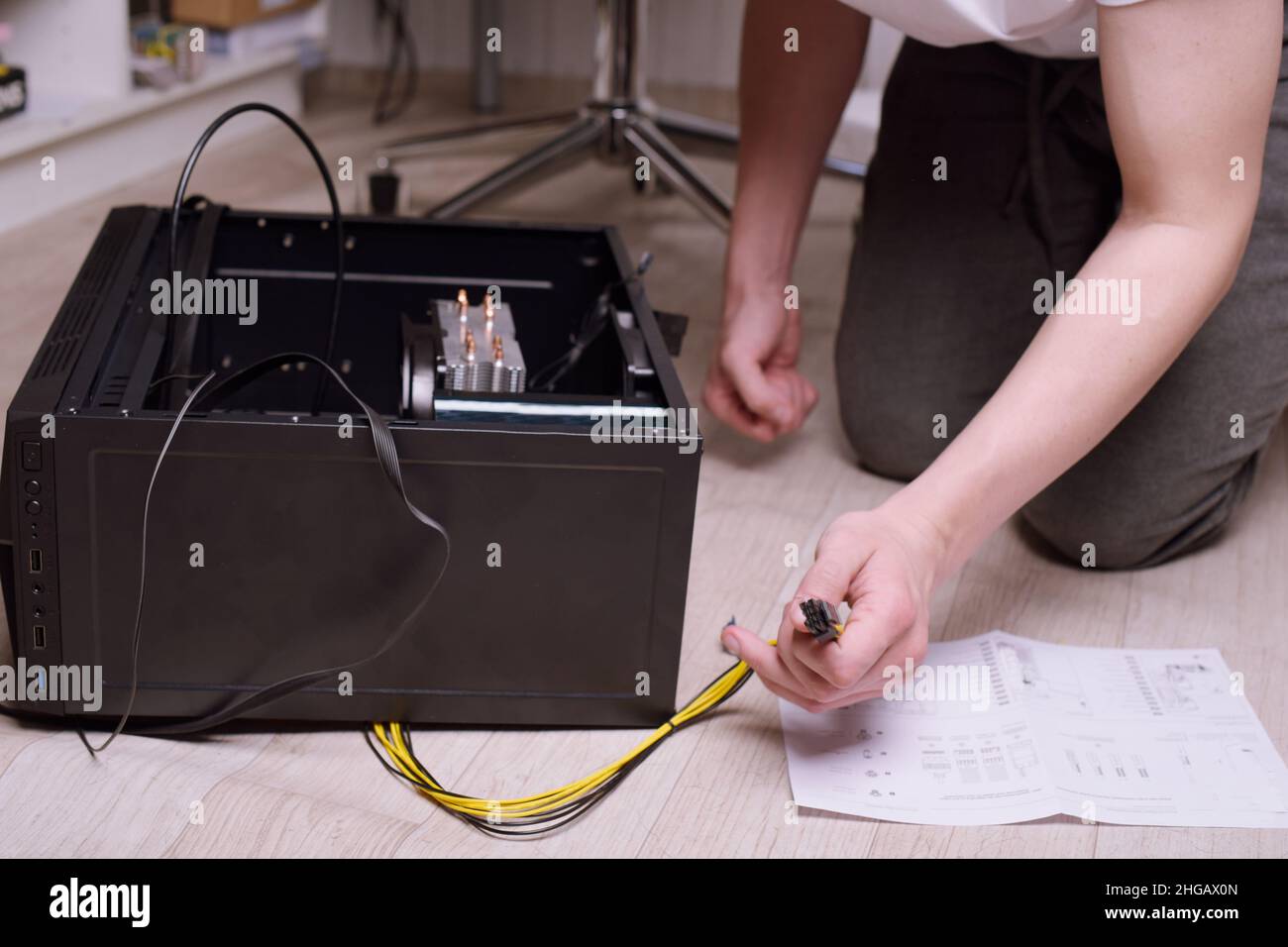 Un uomo a casa raccoglie, disassembla un computer. Le mani di un uomo tengono i fili, collegano i fili. Raccolta di un computer per i professionisti, un computer da gioco Foto Stock