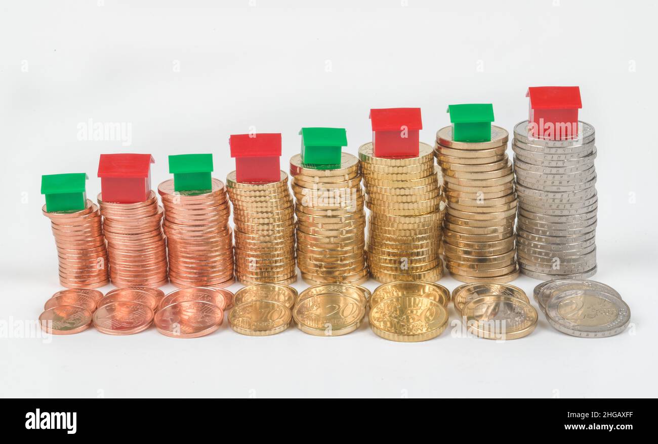 Soldi, euro, monete in euro, case in miniatura, foto simbolo acquisto immobiliare, studio shot Foto Stock