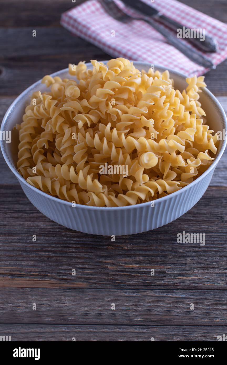 Pasta italiana cruda e cruda isolata su tavola di legno. Immagine verticale Foto Stock
