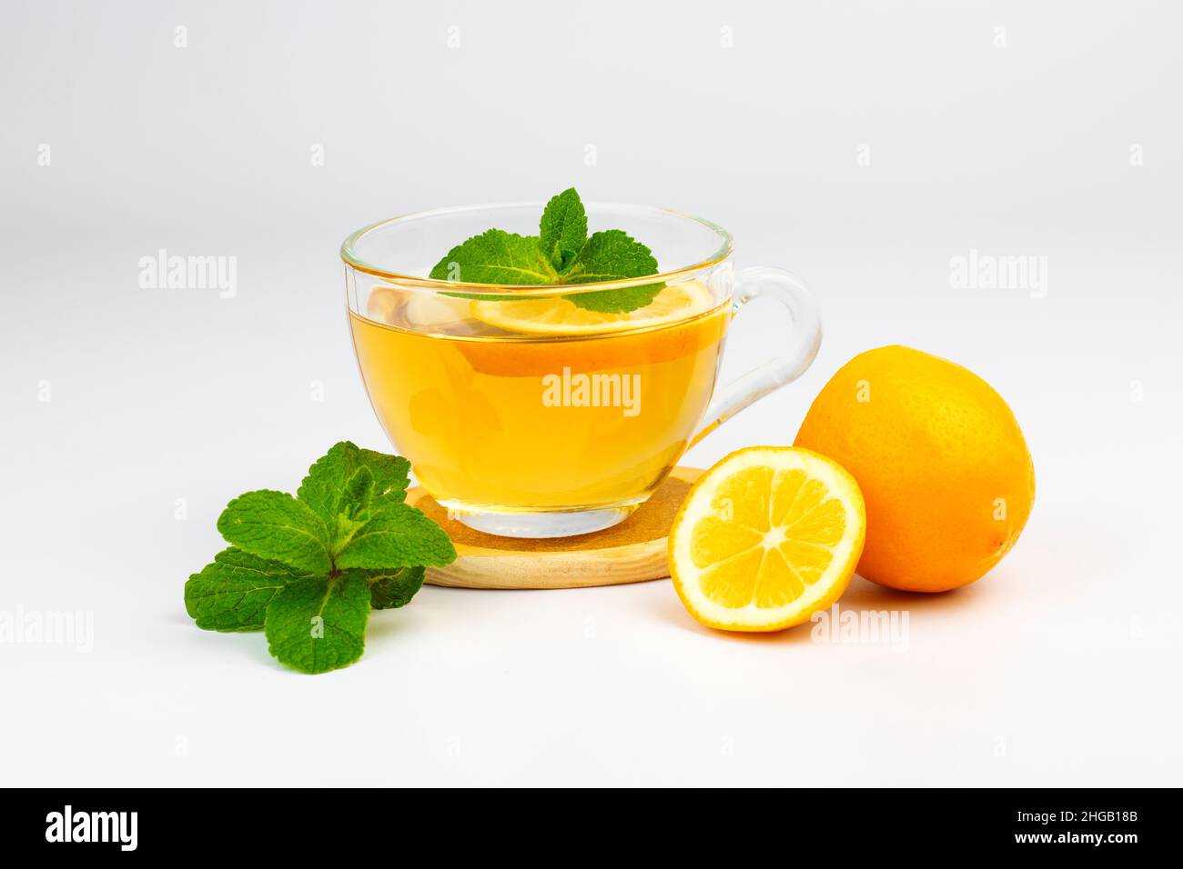 Tazza di vetro trasparente con tè aromatico, foglie di menta e fetta di limone isolato su sfondo bianco. Parte del set. Foto Stock