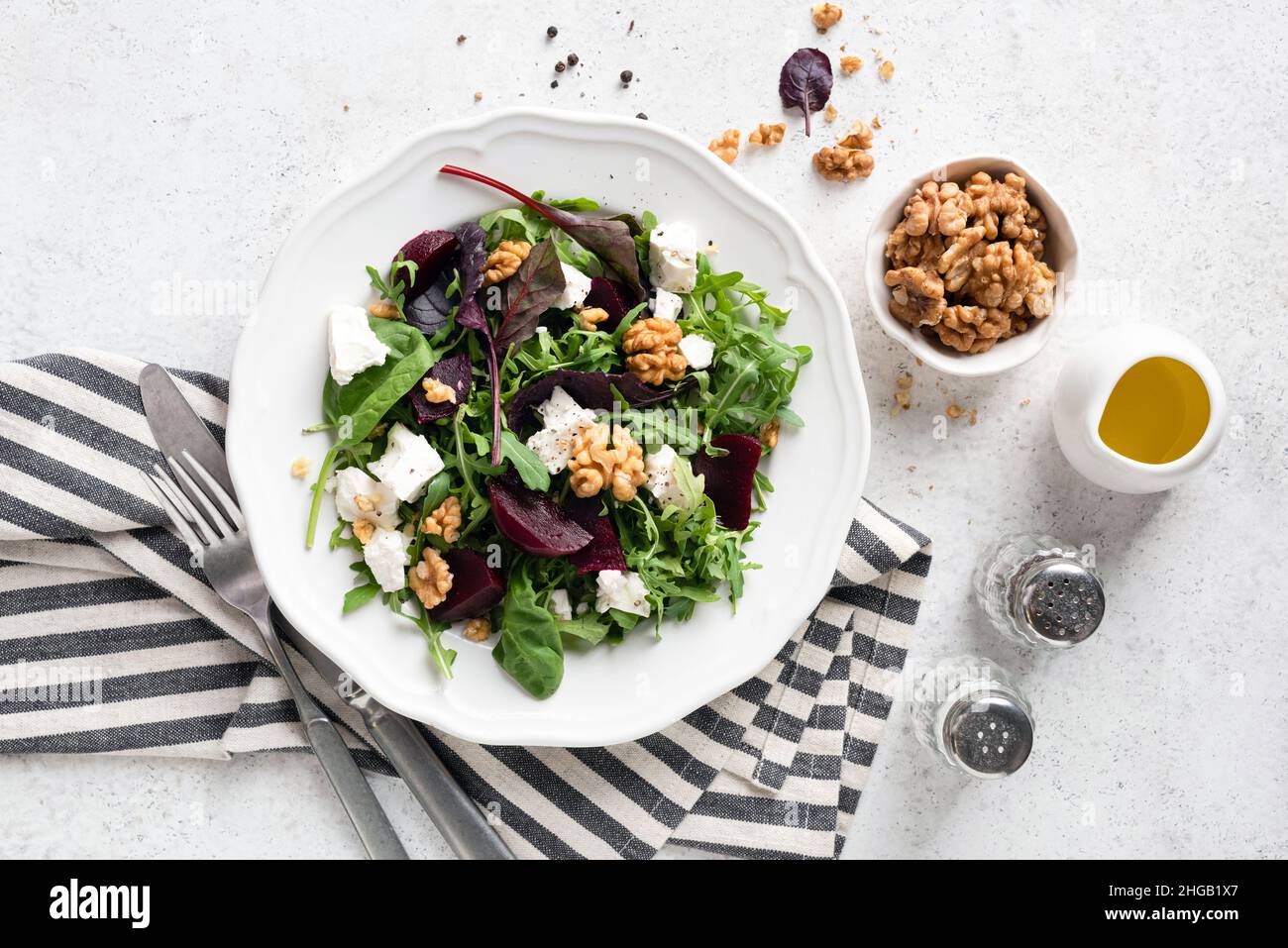 Insalata sana con barbabietola, formaggio feta, noci e rucola su piatto bianco, sfondo grigio tavolo in cemento, vista dall'alto Foto Stock