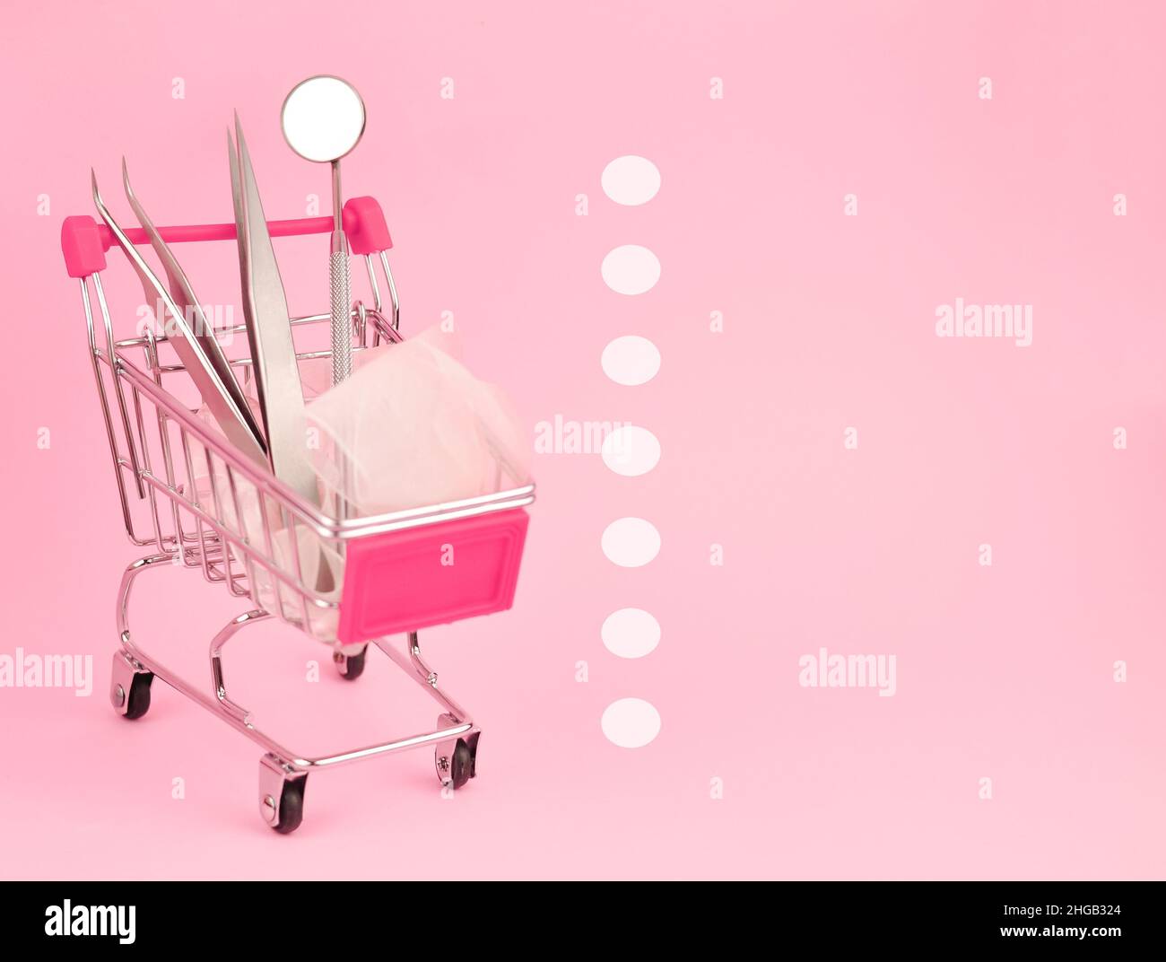 Carrello con pinzette sullo spazio di copia su sfondo rosa Foto Stock