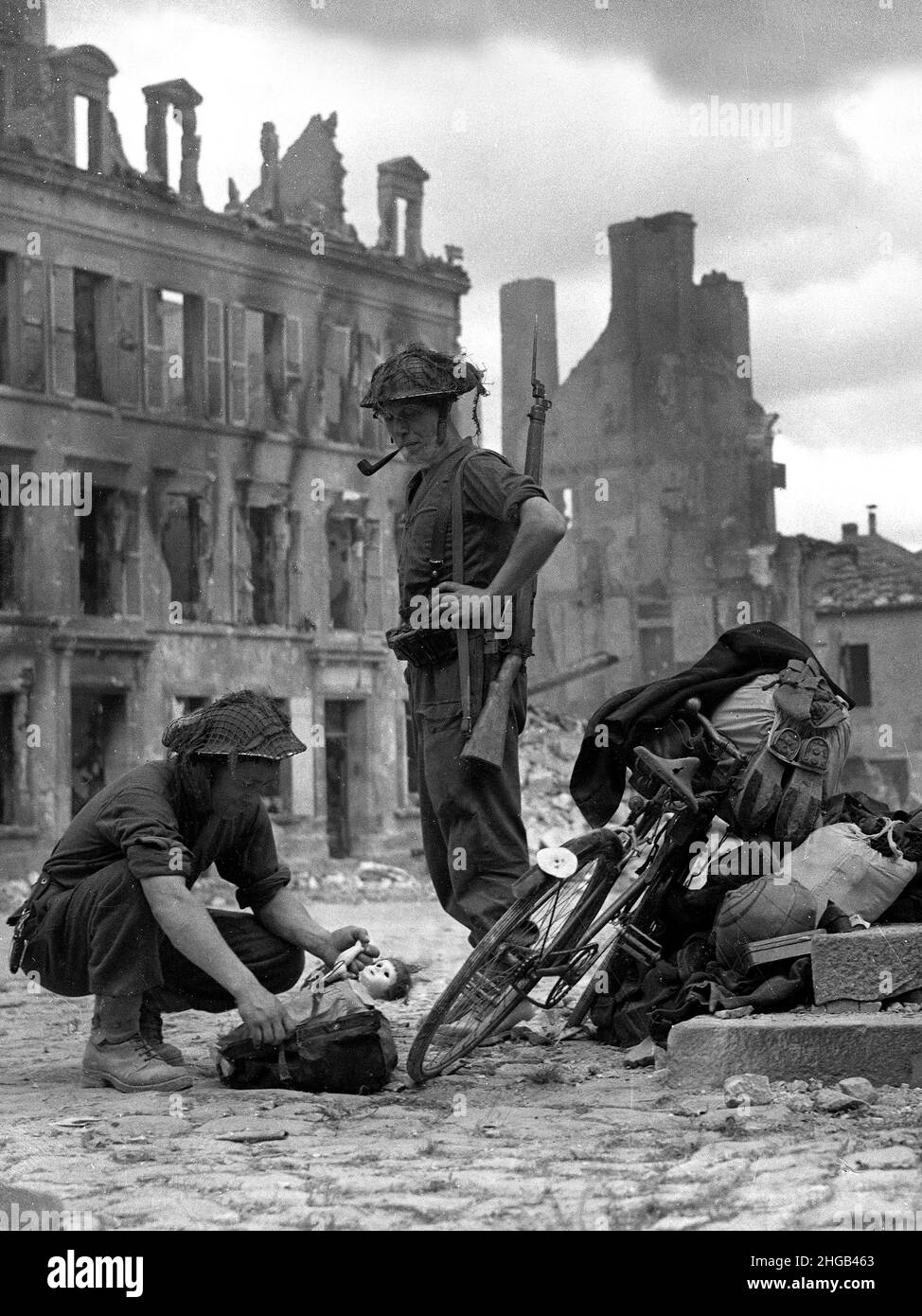 Francia settentrionale seconda guerra mondiale 1944 soldati britannici che guardano una bambola di bambini trovata con una bicicletta di civili che cercano di fuggire. FILE PIÙ GRANDI DISPONIBILI SU RICHIESTA Foto Stock