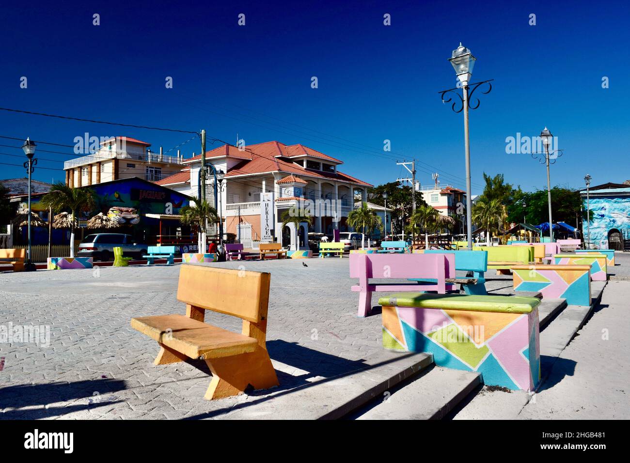 Piazza della Città di San Pedro/Central Park con panchine pastello, una torre dell'orologio, ed edifici in Belize. Foto Stock