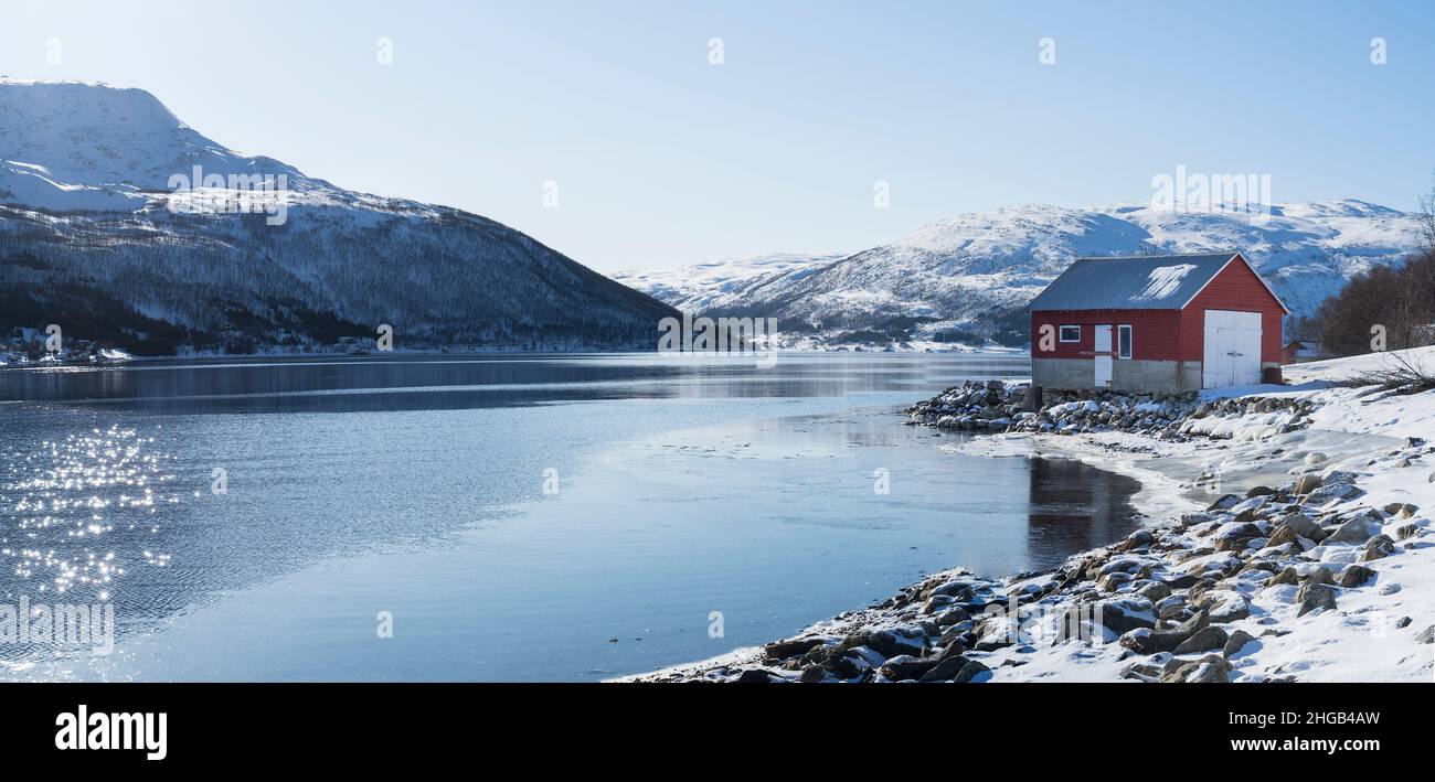 Vista lungo il fiordo con un boathouse rosso a Nordfjordsbotn, Kvaloya, Tromso, Norvegia Foto Stock