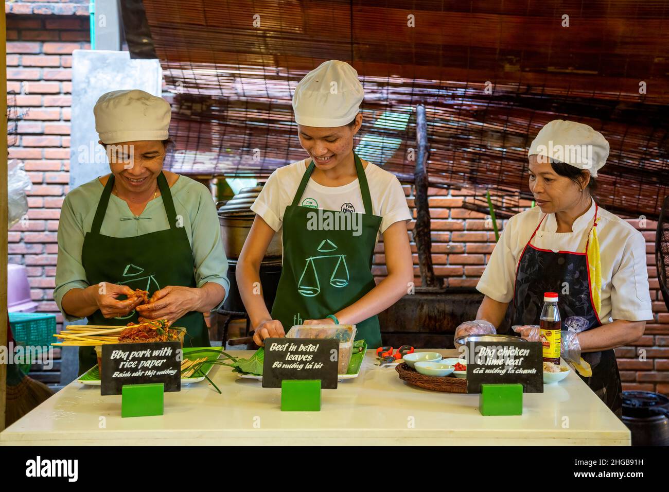 Donne che fanno dimostrazione di cucina, Miss Vy's Cooking Academy, Market Restaurant, Hoi An, Vietnam Foto Stock