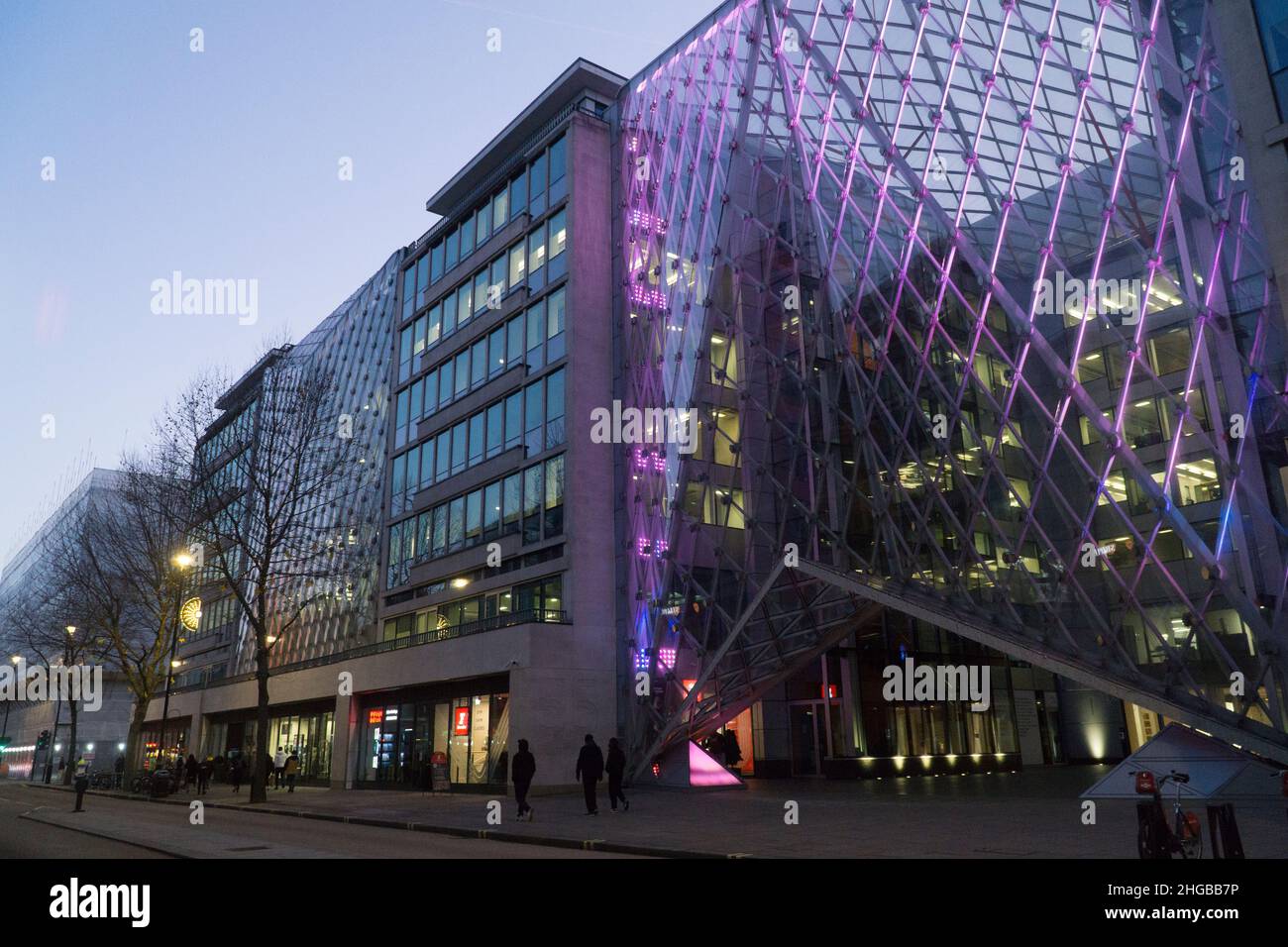 L'atrio del 55 di Baker Street, Londra, presenta luci viola tra i pannelli di vetro e guarda al crepuscolo mentre i pedoni e gli autobus passano Foto Stock