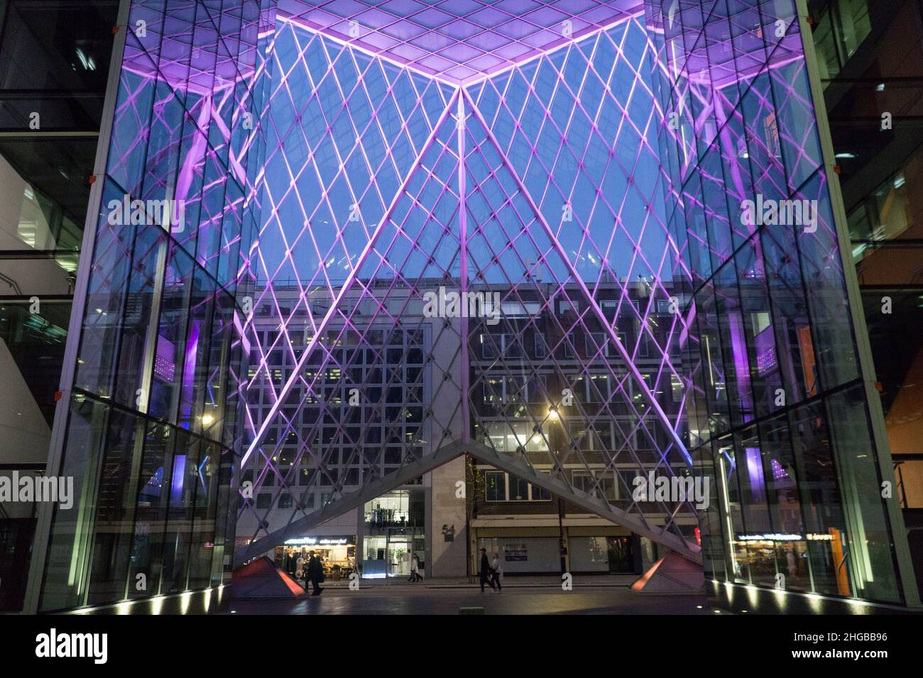 L'atrio del 55 di Baker Street, Londra, presenta luci viola tra i pannelli di vetro e guarda al crepuscolo mentre i pedoni e gli autobus passano Foto Stock