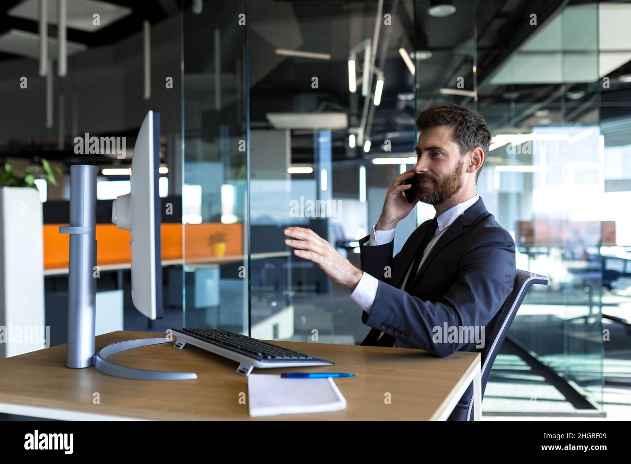 Serio e pensieroso imprenditore maschile che lavora in ufficio al computer in un tuta aziendale Foto Stock