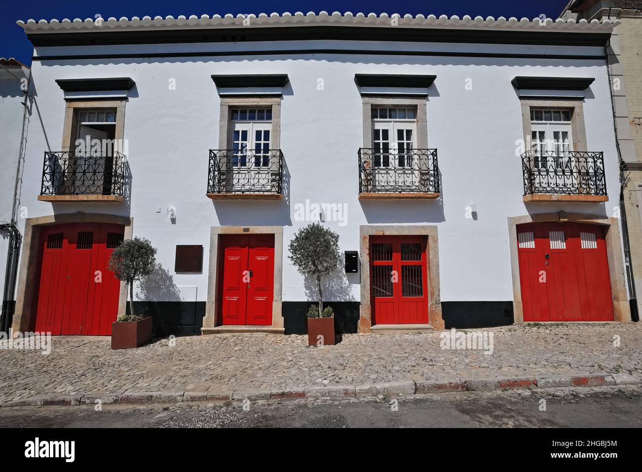Facciata dipinta di bianco-casa cittadina vernacolare-porte rosse-quattro balconi con ringhiere in ferro battuto. Tavira-Portogallo-069 Foto Stock