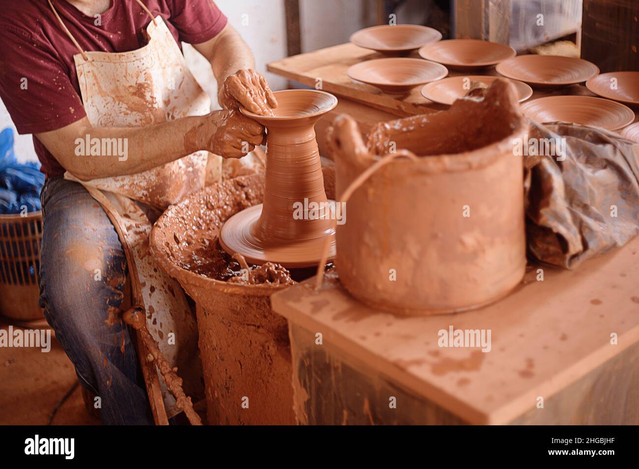 Un uomo scolpisce di argilla. Un uomo scolpisce argilla, piatti, tazze, mestoli. Foto Stock
