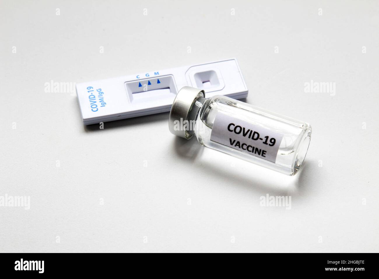 Cassetta per test diagnostico con antigene rapido di Coronavirus SARS-COV-2 Covid-19 e flaconcino con vaccino su sfondo bianco Foto Stock