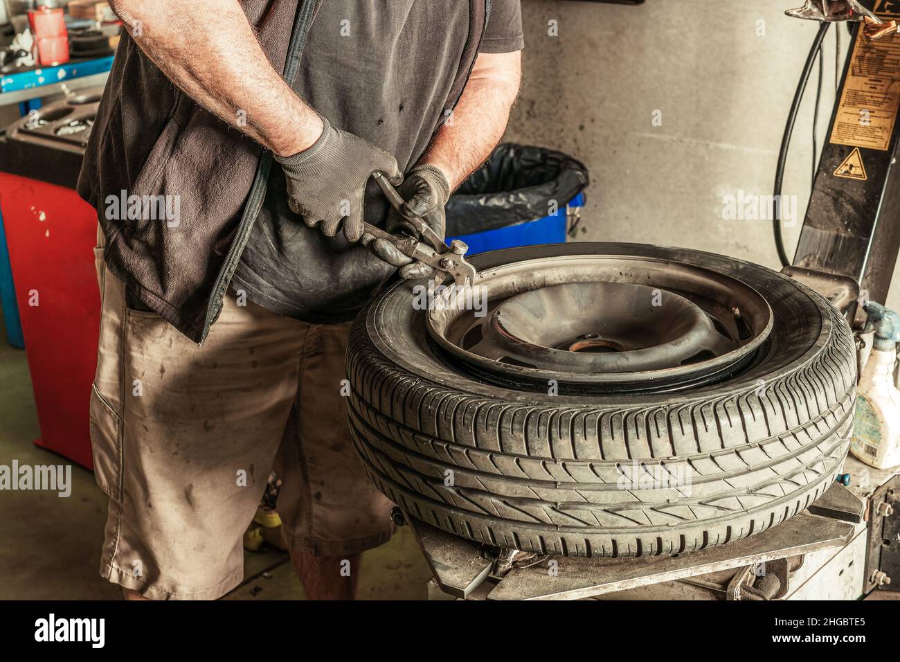 Il meccanico rimuove i cavi dalla ruota in un'officina Foto Stock