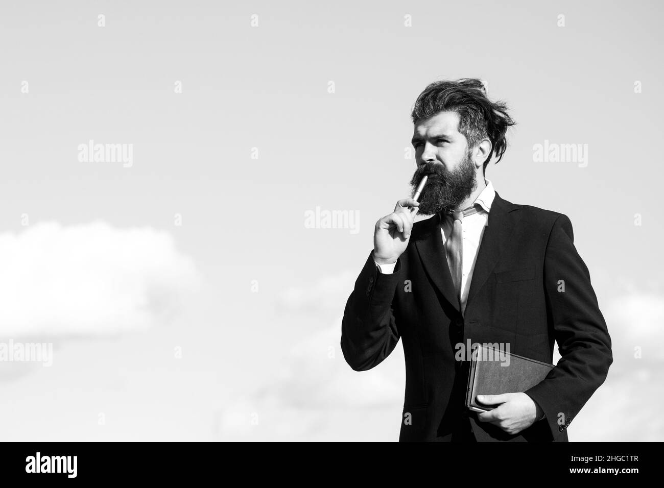 Uomo d'affari con cielo. L'uomo d'affari sta pensando a qualcosa con la matita. Sogni d'affari. Un giovane premuroso in camicia e tie con tie per appunti Foto Stock