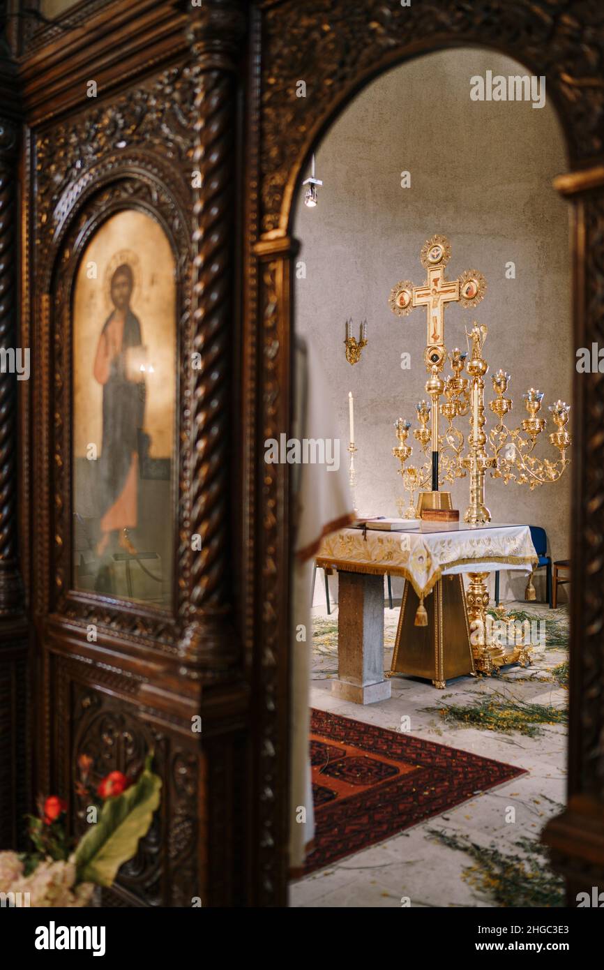 Candelabro d'oro su un tavolo di fronte a una croce nella Chiesa di San Sava in Tivat. Vista attraverso l'arco Foto Stock