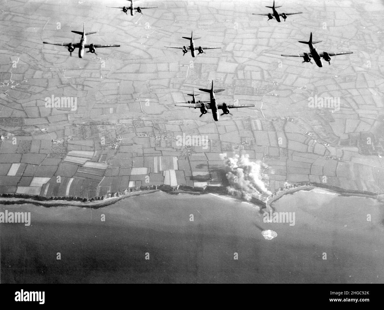 A-20 i bombardieri dell'Havoc dall'Aeronautica militare del 9th bombardano Pointe du Hoc prima degli sbarchi del D-Day. Il fumo è visibile dalle fortificazioni sulle scogliere. La spiaggia di Omaha si trova al centro della foto, a sinistra di Pointe du Hoc Foto Stock