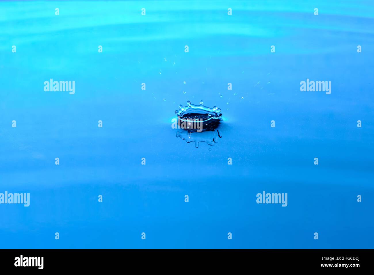 Spruzzi acqua dopo goccia cade.sfondo blu astratto con goccia in acqua Foto Stock