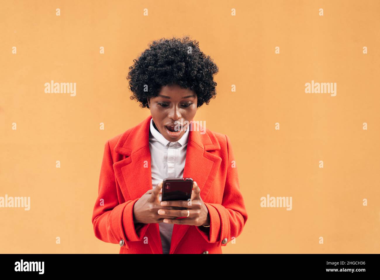Scioccata donna afro guardando sorpreso il suo telefono cellulare. Foto Stock