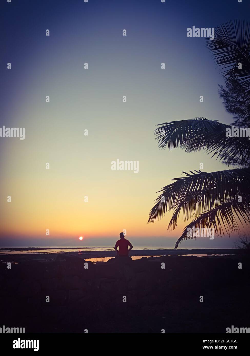 Uomo relax sulla spiaggia al tramonto Foto Stock