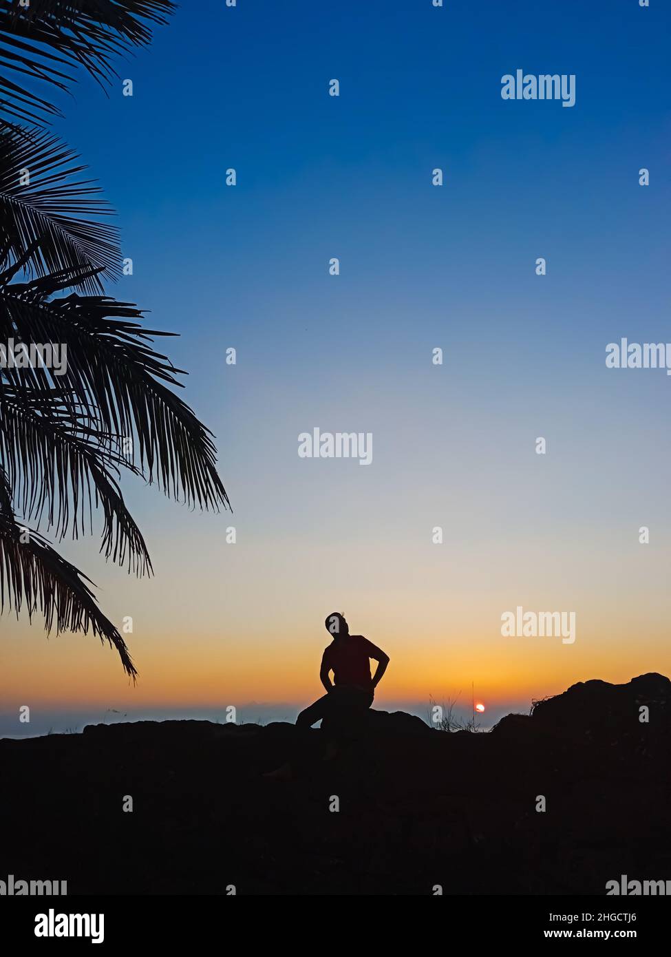 Uomo relax e seduta sulla spiaggia nel bellissimo tramonto Foto Stock