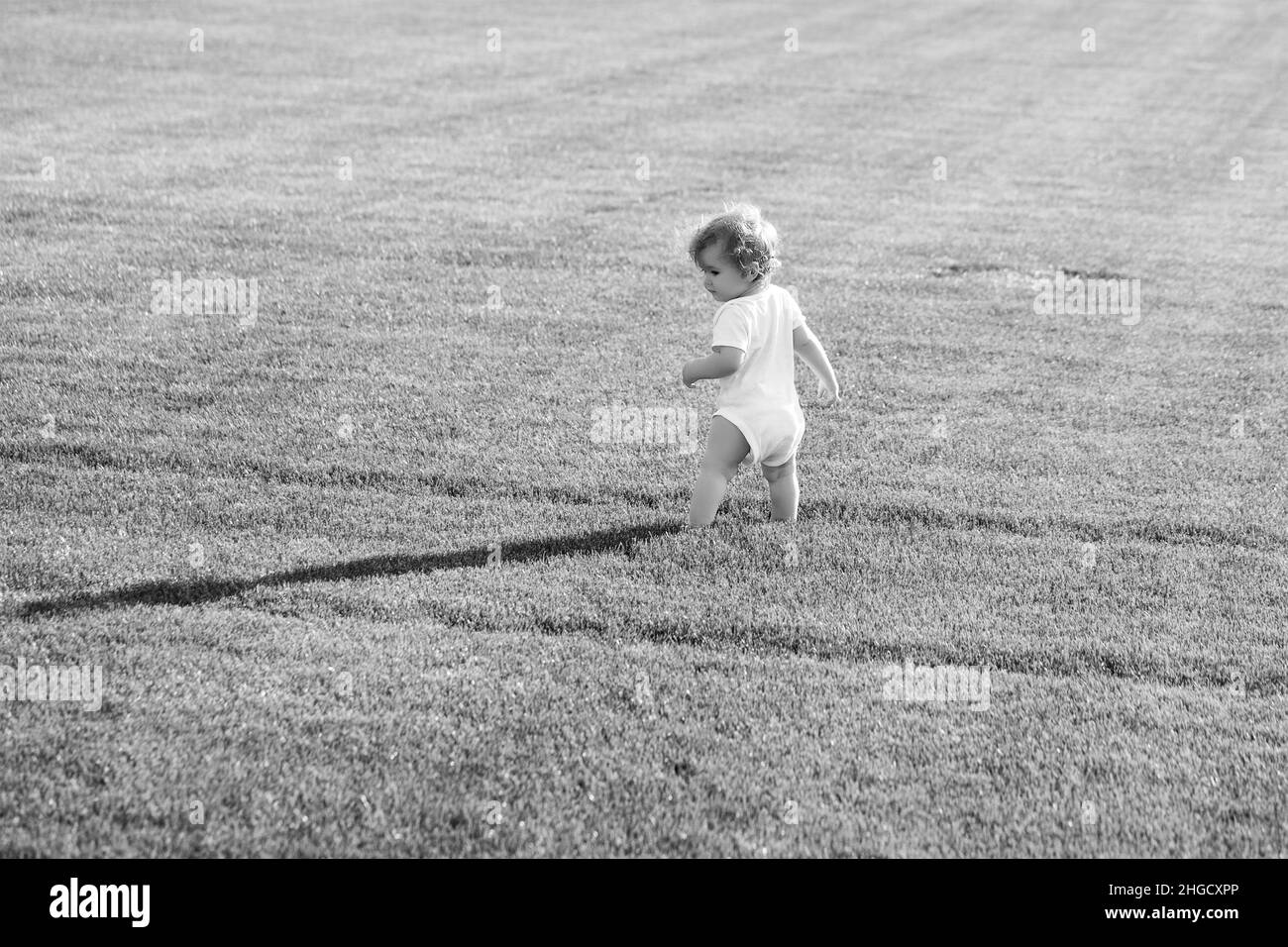 Vista posteriore di infanzia felice e l'assistenza sanitaria infantile. Bambino in un bellissimo campo primaverile verde. Foto Stock