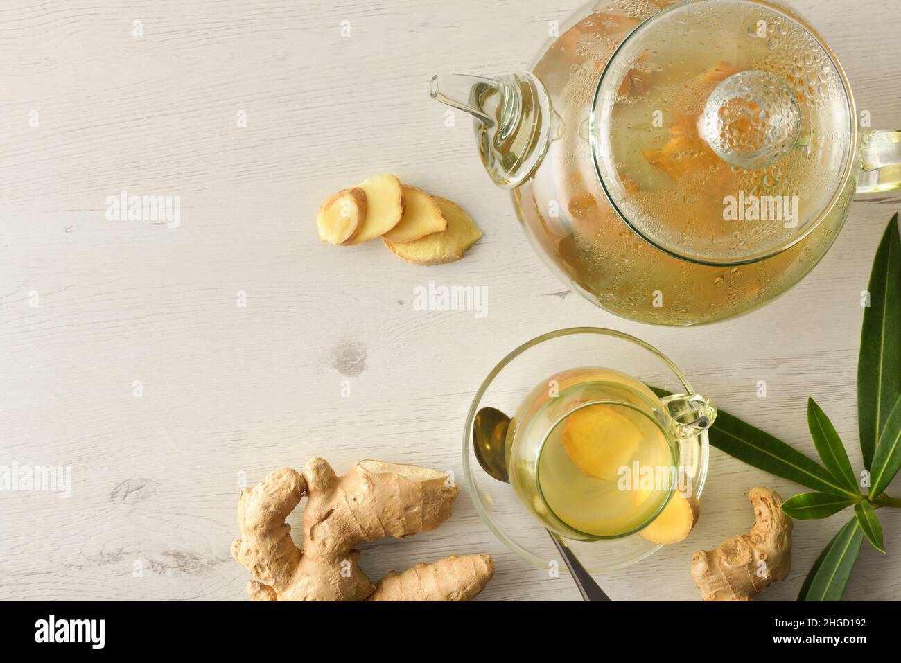 Tazza per bevande calde su un tavolo bianco con radice di zenzero affettata e teiera. Vista dall'alto. Foto Stock