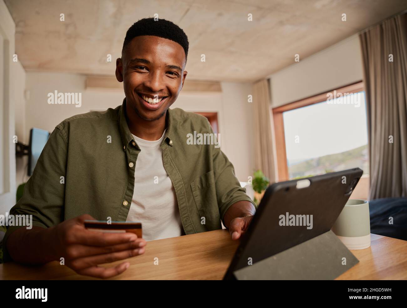 Ritratto di felice giovane adulto nero maschio utilizzando tablet elettronico per fare acquisti online in casa moderna. Foto Stock