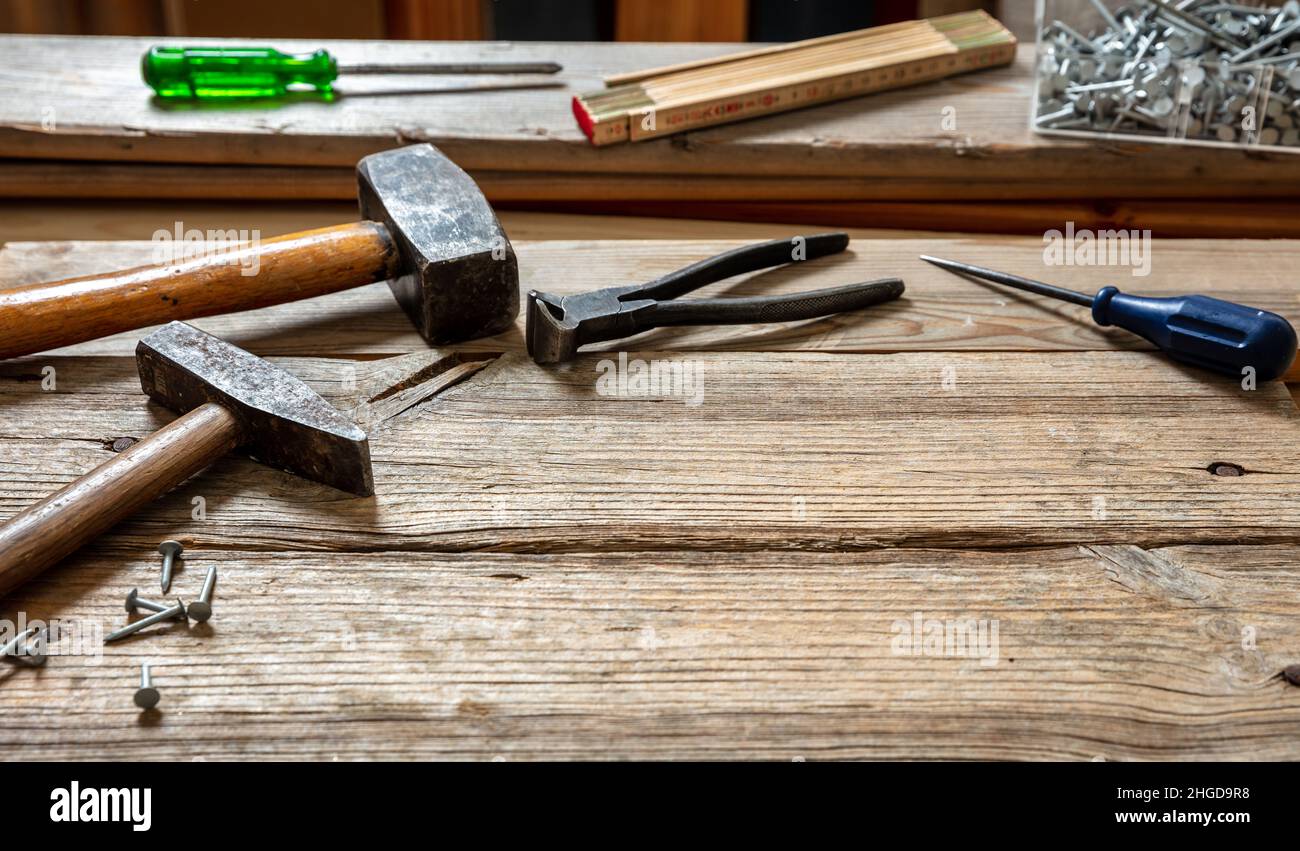 Attrezzatura usata, martello, pinze a martello e chiodo su legno, tavolo da banco da officina carpentiere, vista closeup Foto Stock
