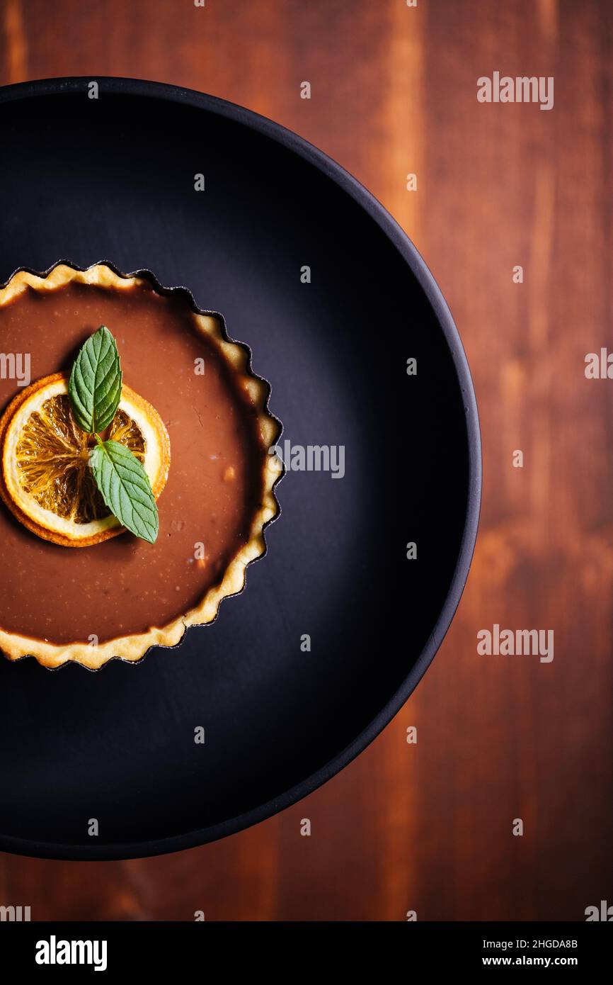 Crostate di cioccolato su sfondo grigio, decorate con foglie di menta e arancio secco Foto Stock