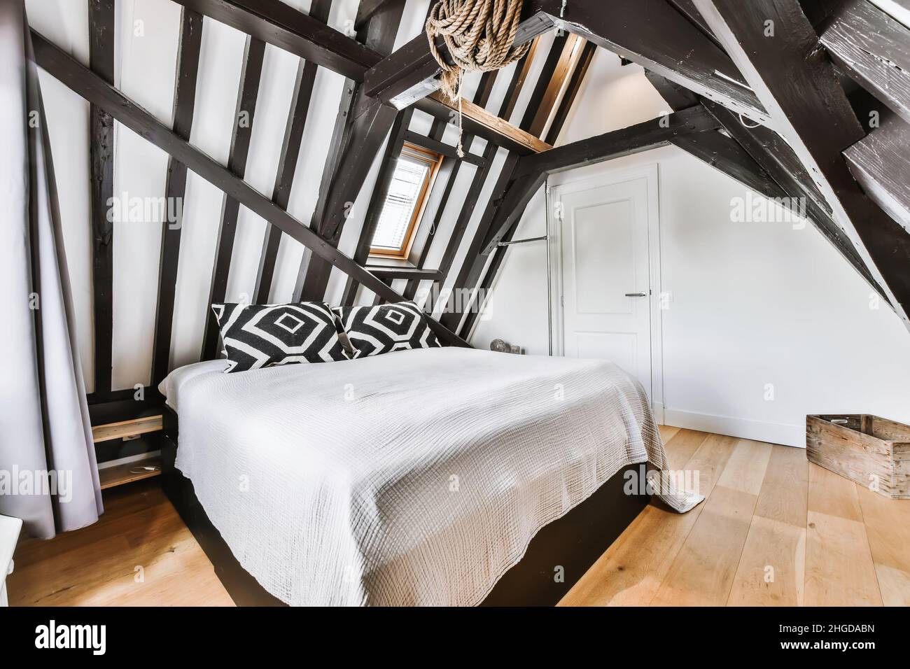 Elegante camera mansardata con travi in legno e un letto morbido Foto Stock