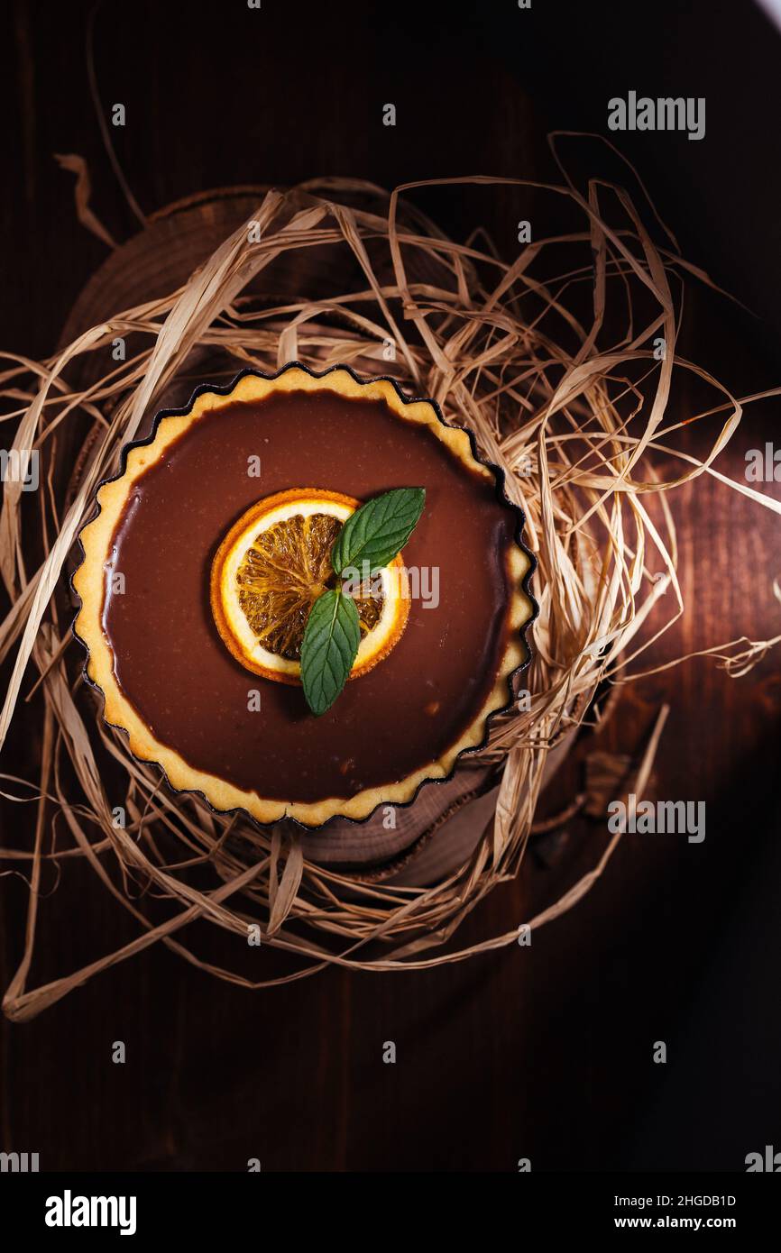 Crostate di cioccolato su sfondo grigio, decorate con foglie di menta e arancio secco Foto Stock