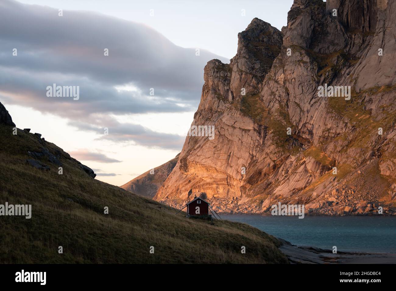Piccola cabina solitaria vicino all'oceano con montagne circostanti. Foto Stock