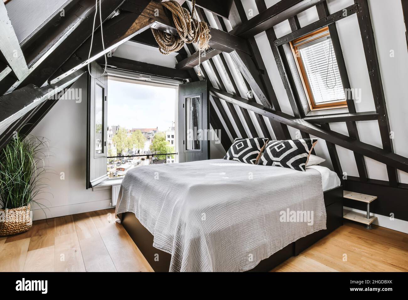 Elegante camera mansardata con travi in legno e un letto morbido Foto Stock