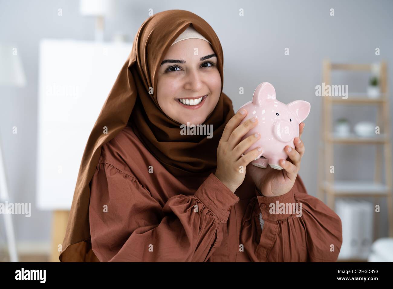 Happy Muslim Woman Holding Piggybank. Risparmio di denaro Foto Stock