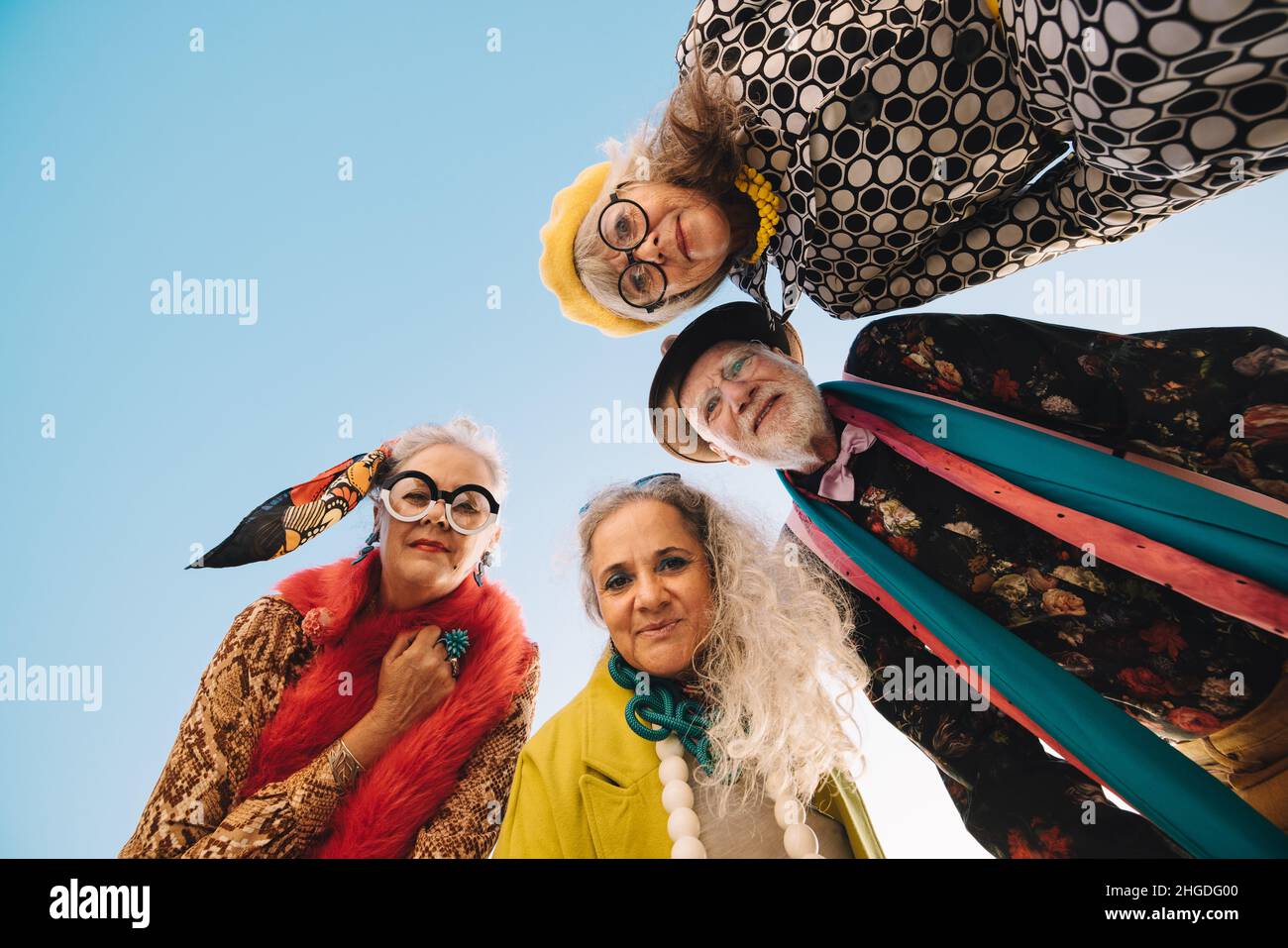 Direttamente sotto la foto di cittadini anziani che guardano la macchina fotografica all'aperto. Gruppo di persone eccentrica anziani che indossano abiti colorati casual. Elegante se Foto Stock