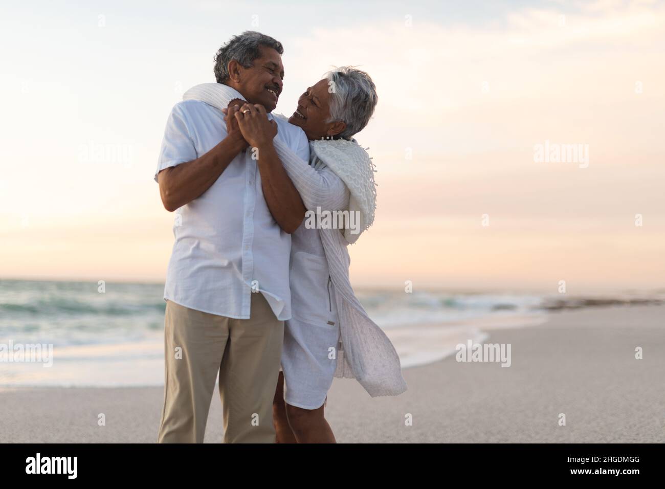 Allegro giovane coppia multirazziale senior che si guarda l'un l'altro mentre abbraccia durante il tramonto Foto Stock