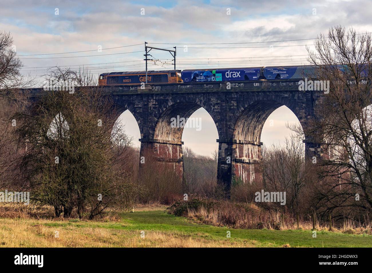 La locomotiva elettrica diesel di classe 60 trasporta il treno a biomassa Drax dal molo di Liverpool attraverso il viadotto della Sankey Valley a Earlestown. Foto Stock