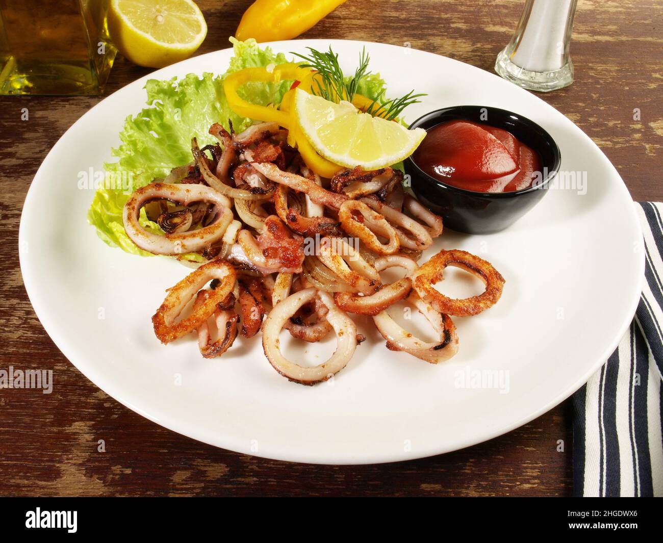 Polpo, Calamari fritti anelli con insalata su un piatto con salsa al peperoncino e limone Foto Stock