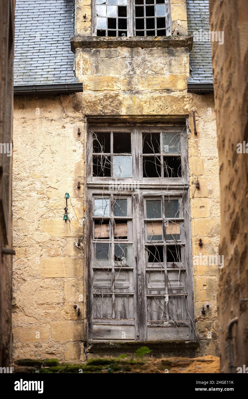 Vecchia casa in pietra derelict con finestre e persiane rotte Foto Stock