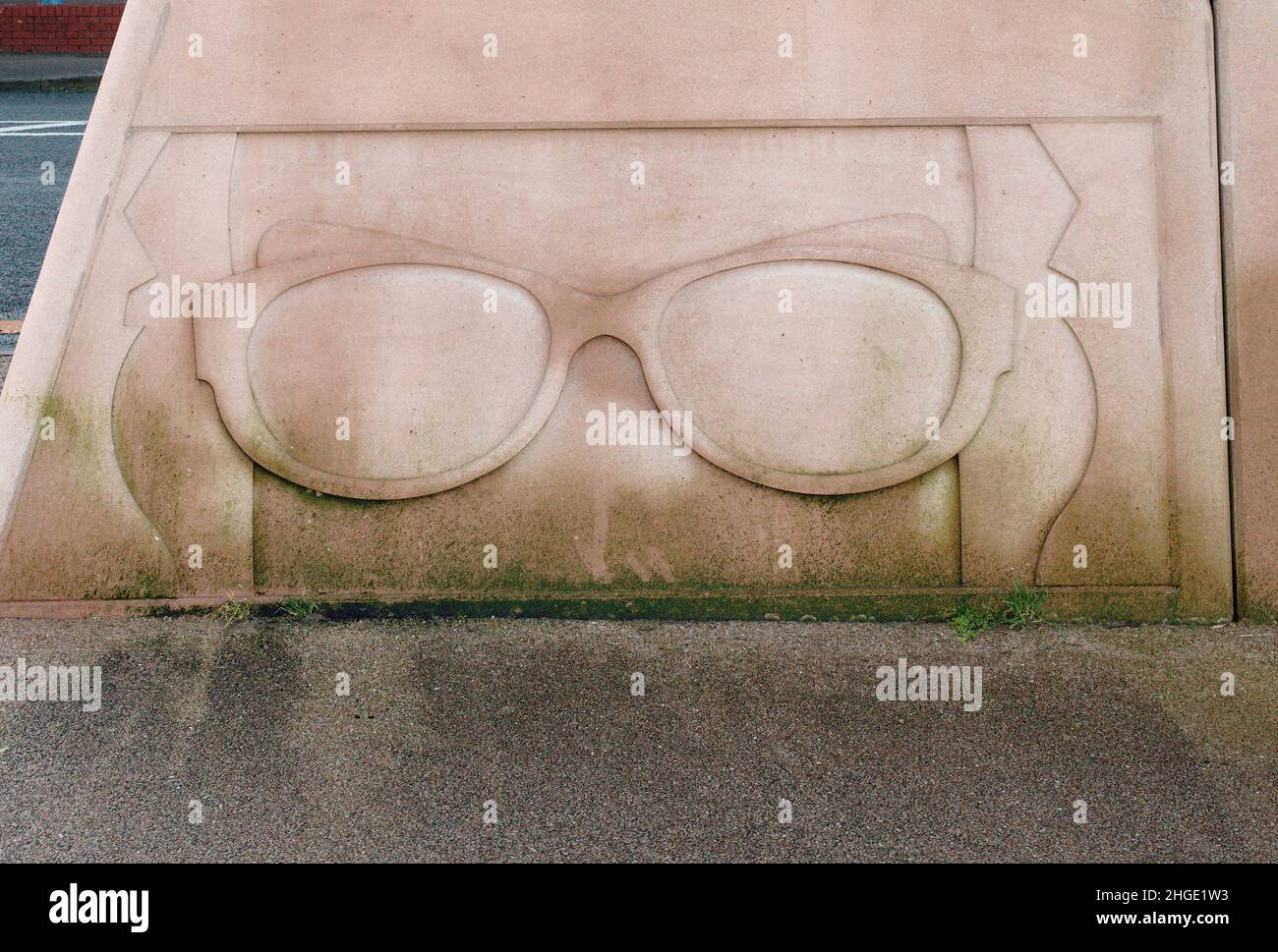 Un paio di occhiali scolpiti nella parete della passeggiata a Morecambe, un tributo al comico Eric Morecambe. Foto Stock
