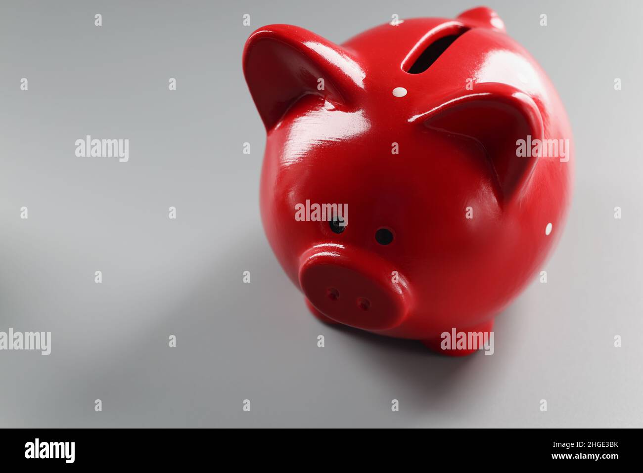 Contenitore piggybank rosso brillante sulla superficie grigia, cosa vuota per mettere soldi Foto Stock