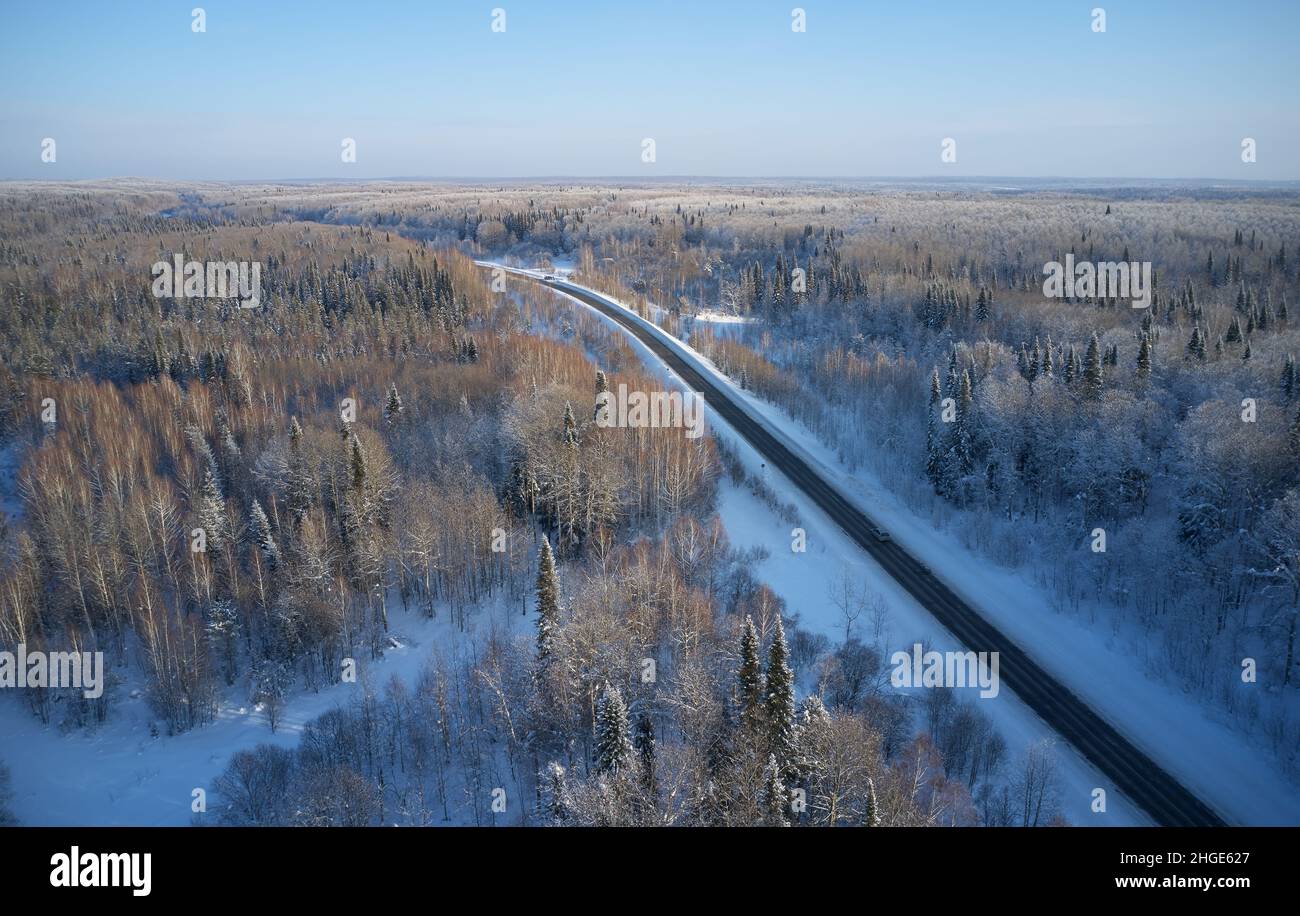 Foto aerea della strada invernale in taiga su Salair Ridge in inverno. Aby sibirica alberi coperti da hoarfrost sorgono sopra la foresta di aspen. Siberia, R. Foto Stock