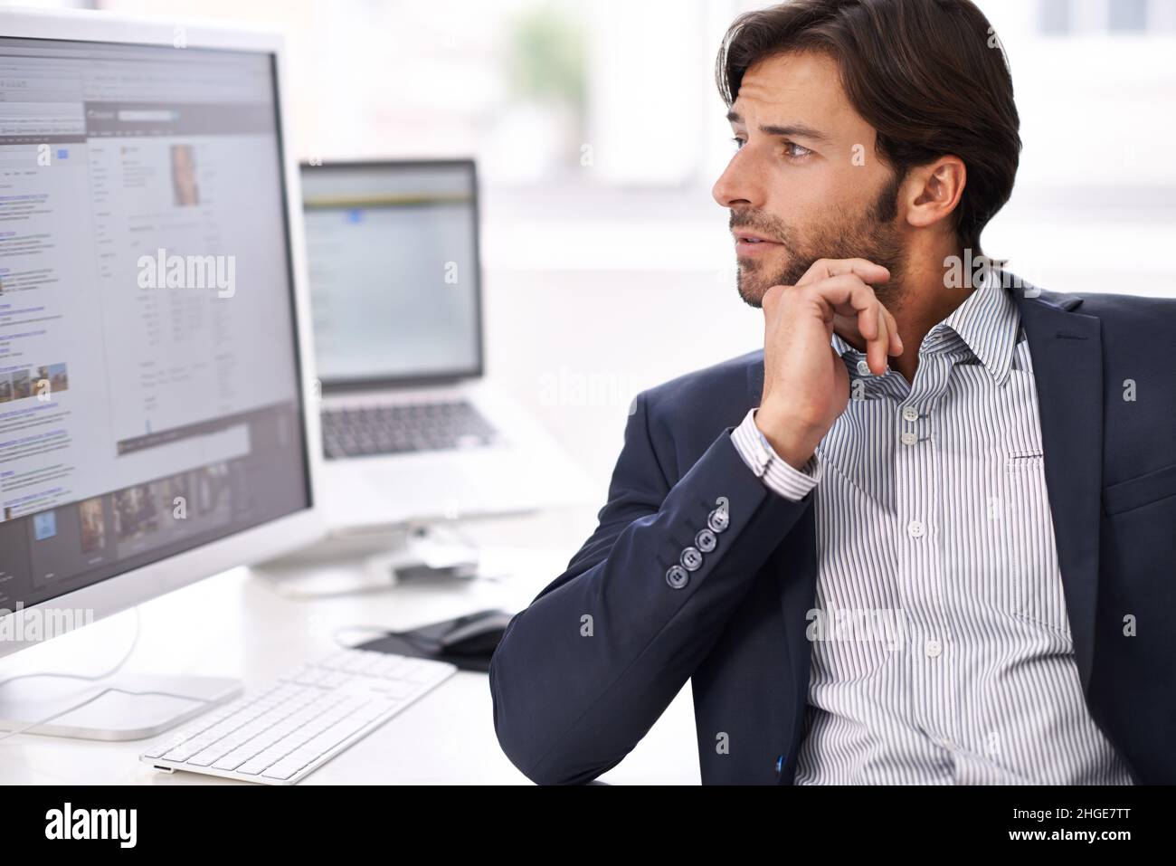 Contemplazione sul posto di lavoro. Un giovane uomo d'affari che fa ricerca sul suo computer. Foto Stock