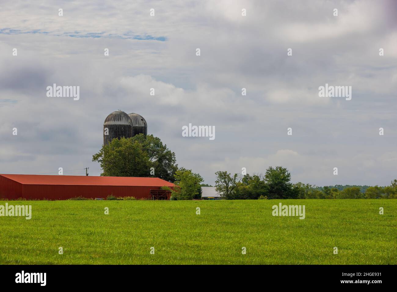 Rural Eastern Tennessee, paesaggio agricolo con silo sito su una collina accanto a un edificio rosso sotto cielo nuvoloso. Foto Stock