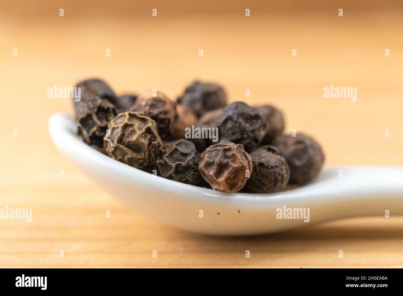 Semi di pepe in un piccolo cucchiaio bianco Foto Stock