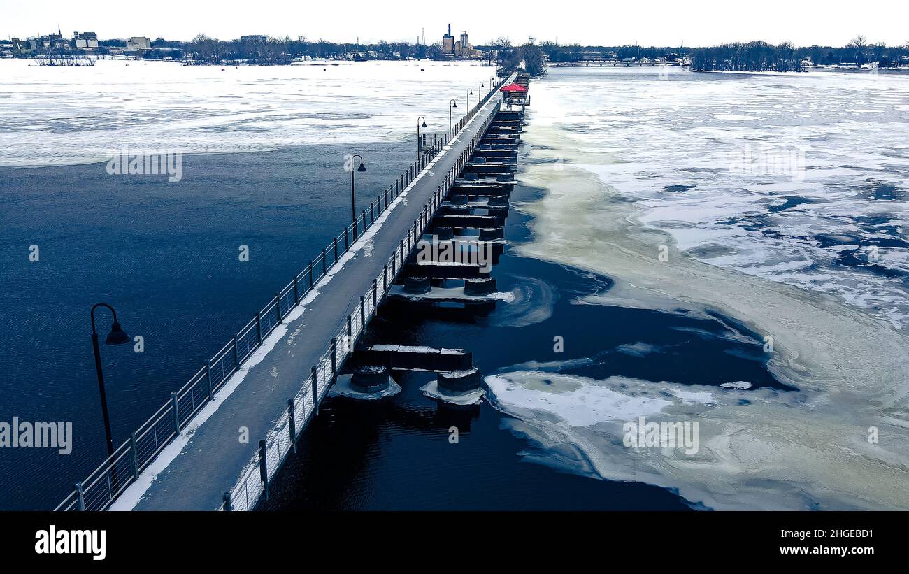 Il paesaggio ghiacciato con sentieri per escursioni/passeggiate si snoda sull'acqua ghiacciata. Il sentiero del trespolo (amicizia) si estende verso un'altra città sul lago. Foto Stock