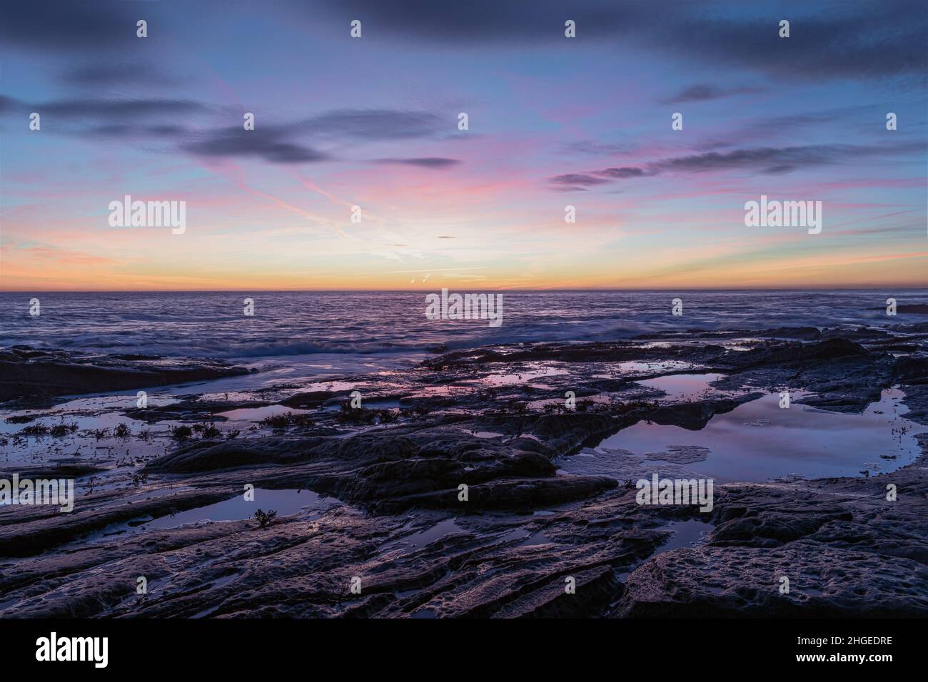 Bellissima alba sulla costa con le onde che si infrangono sulle rocce Foto Stock
