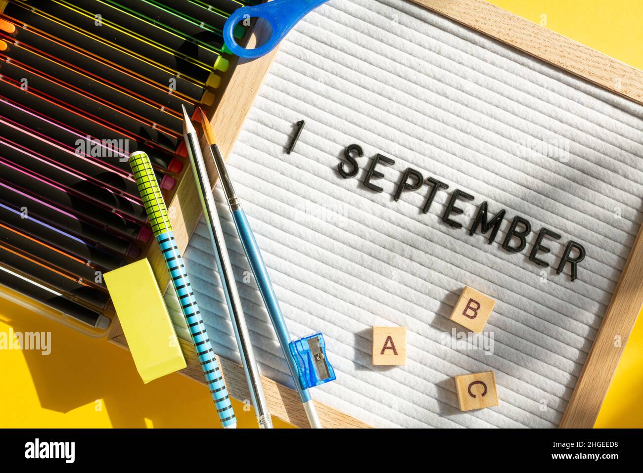 1 settembre lettera bordo con forniture scolastiche come penne, forbici, ABC, vernici su sfondo giallo. Istruzione. Giornata di conoscenza, studio, ritorno a scuola con Foto Stock