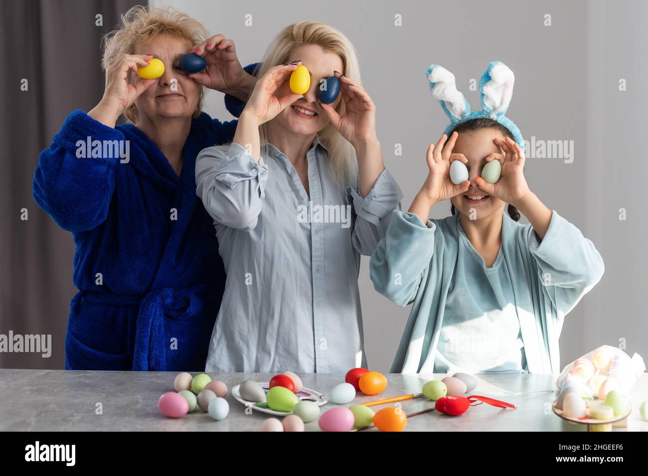 Sorridendo felice nonna caucasica, madre e figlia dipingere e decorare le uova di Pasqua avendo grande tempo insieme in cucina domestica Foto Stock