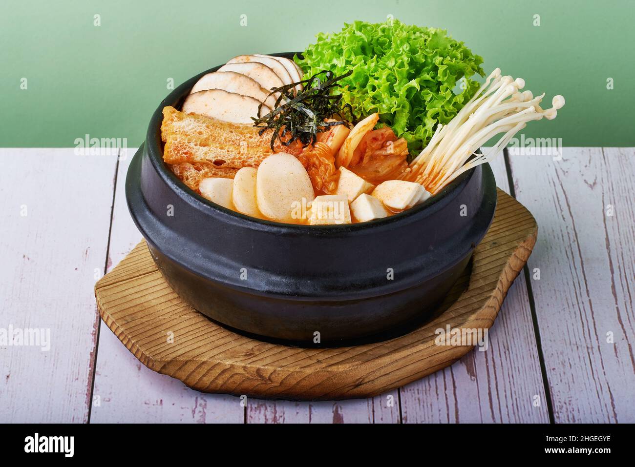 Cibo coreano Ramen Kimchi jjigae con pancia di maiale alla griglia e ramen in una ciotola di metallo nero su sfondo di legno Foto Stock